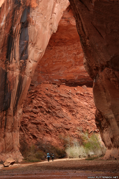 Two backpackers approach the base of Jacob Hamblin arch
