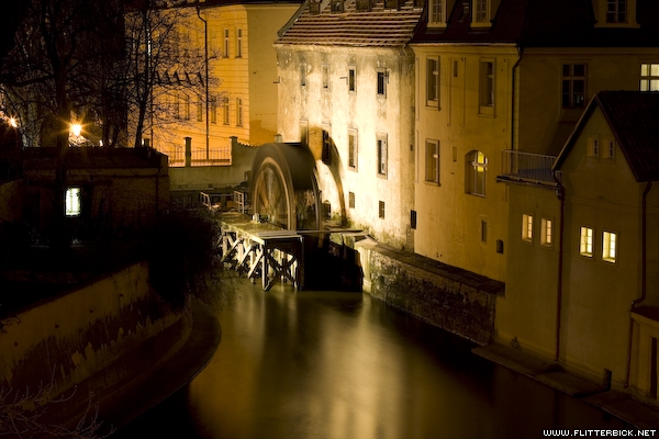 A water mill spins through the night near the Charles Bridge